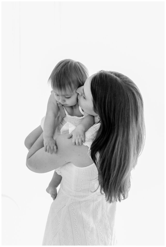 A mother kissing her baby on the cheek by DC Baby Photographer