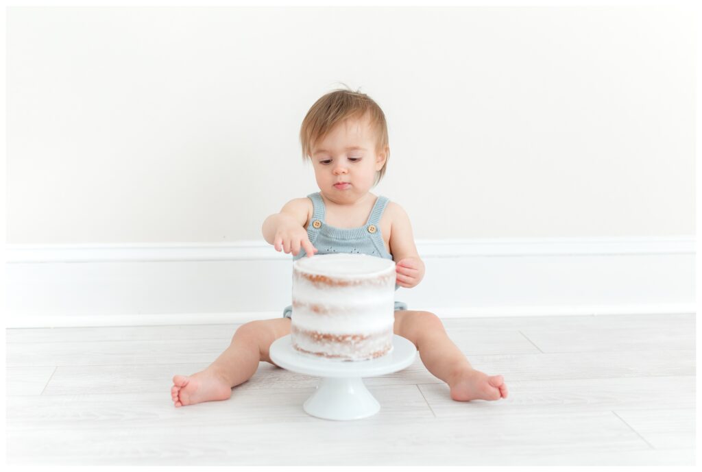 A baby looking at a cake smash cake by Virginia Baby Photographer