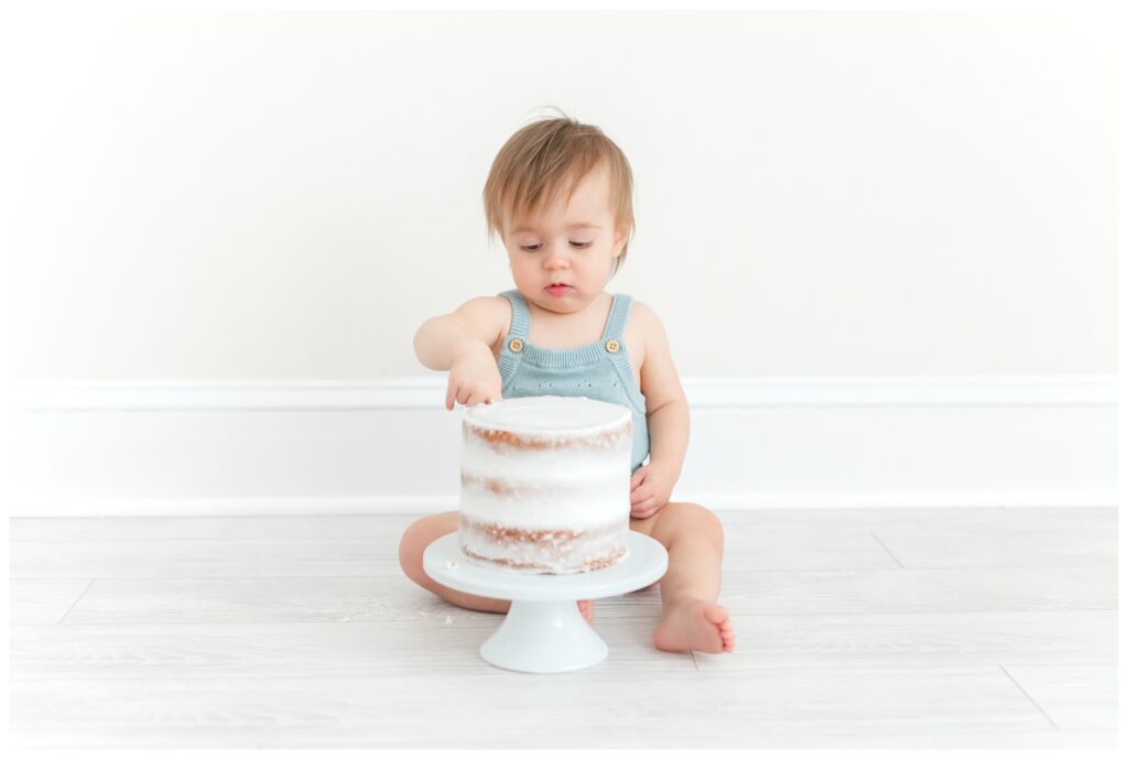 A photo of a baby sticking its finger in a cake by DC Baby Photographer