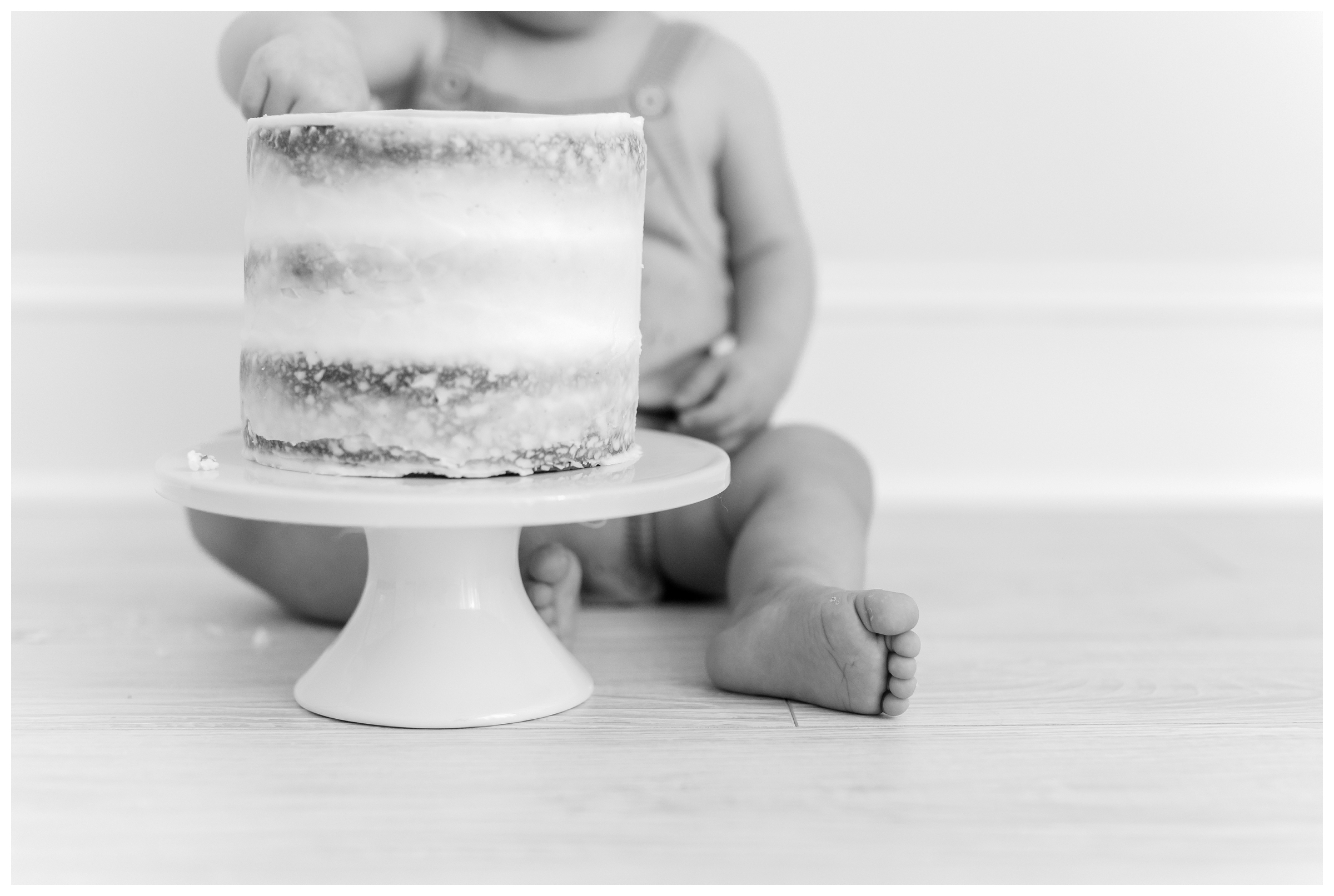 Black and white photo of a baby smashing a cake by DC Baby Photographer