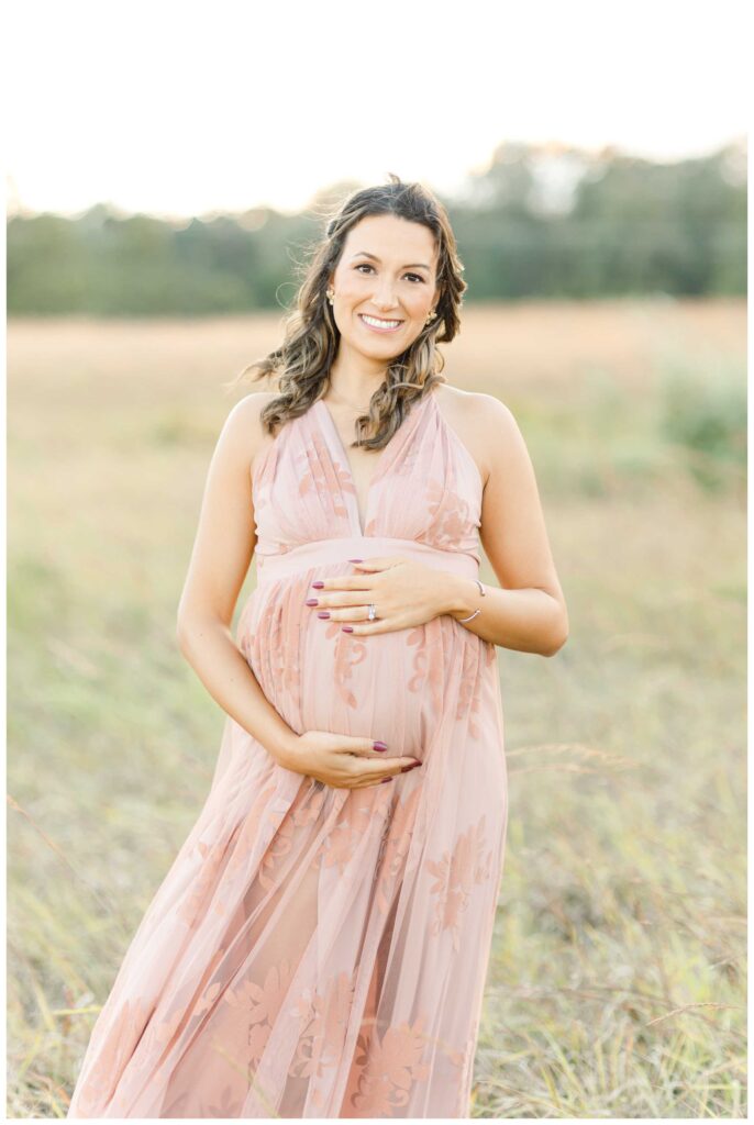 A pregnant woman wearing a deep cup pink lace dress posing outside for her Northern Virginia Maternity Photographer