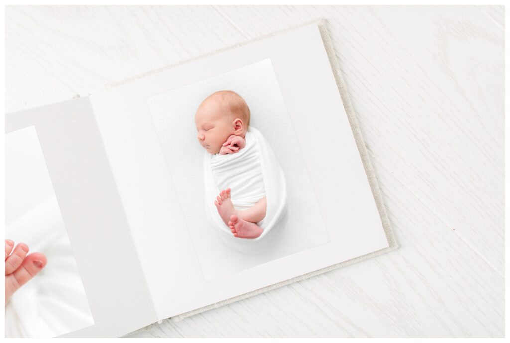 A close-up photo showing a baby album with newborn portraits inside by Jessica Green Photography